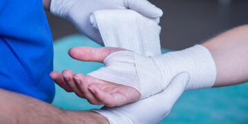 Close-up of male doctor bandaging a hand