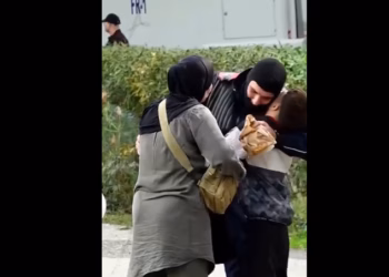 Rama ndan pamje, një grua dhe një djalë i dërgojnë ushqim policit në detyrë